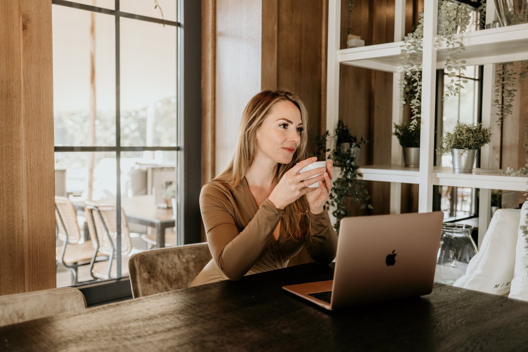 Joyce Nijsse aan tafel met een kop thee en haar laptop